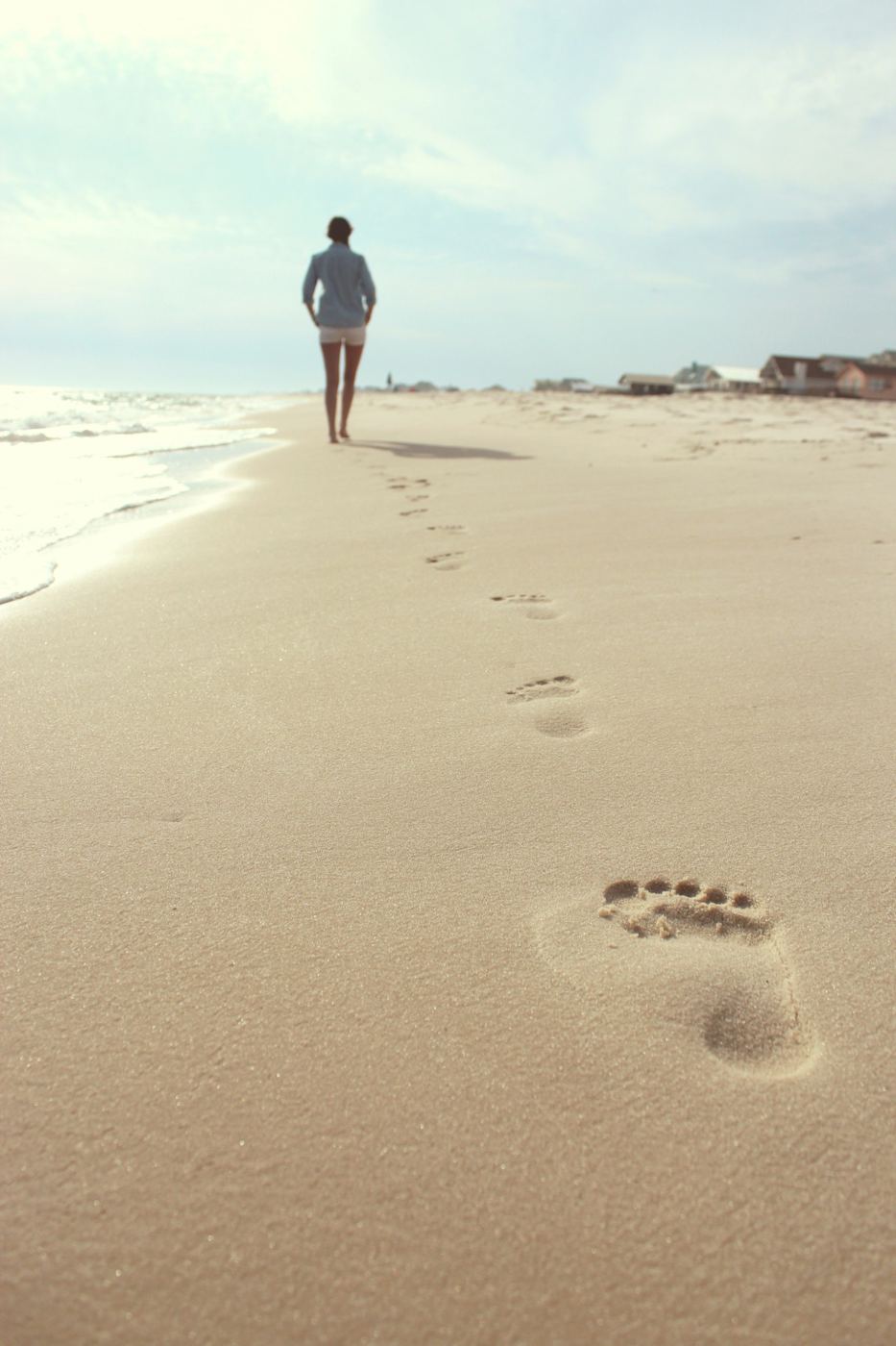Footprints in pale sand leading to a walker
